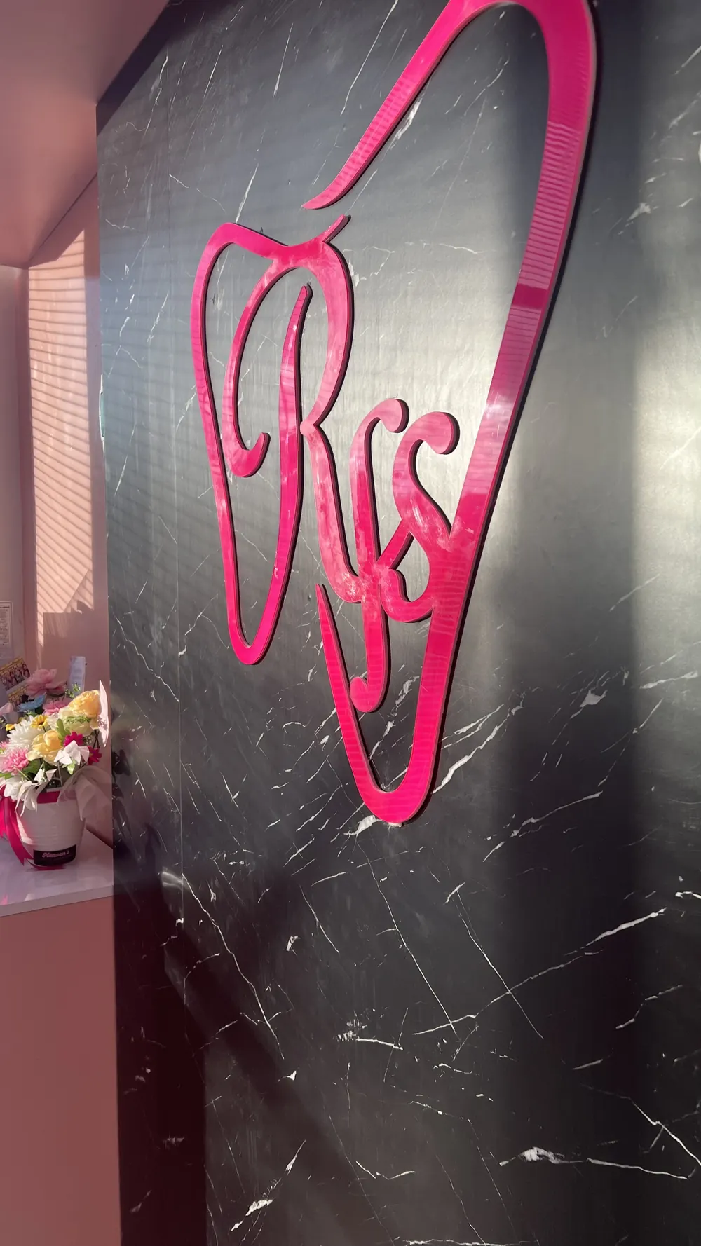 Logo RFS berwarna pink di dinding marmer hitam