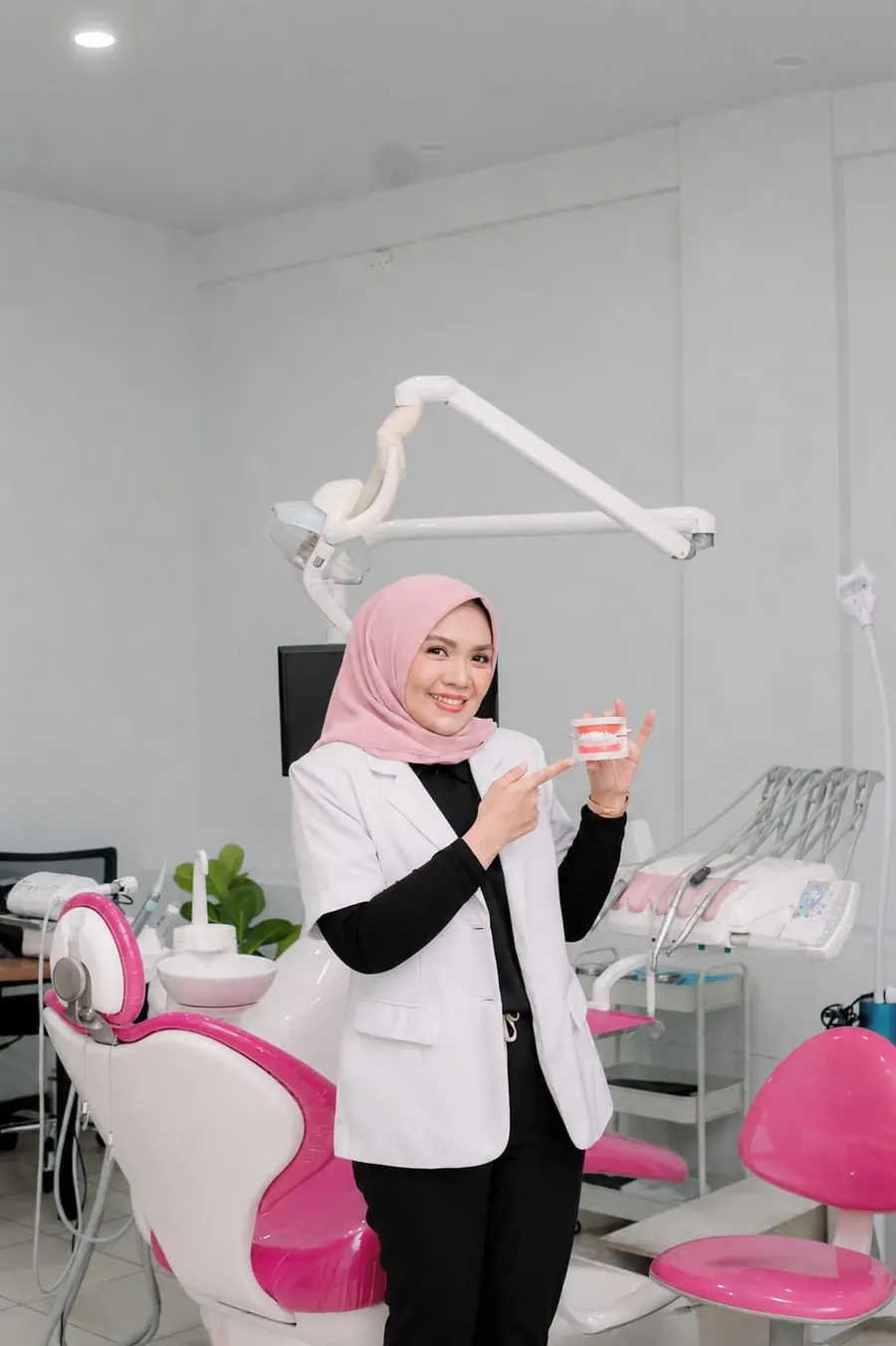 drg. Richa F. Sari tersenyum memegang model gigi di ruang praktik